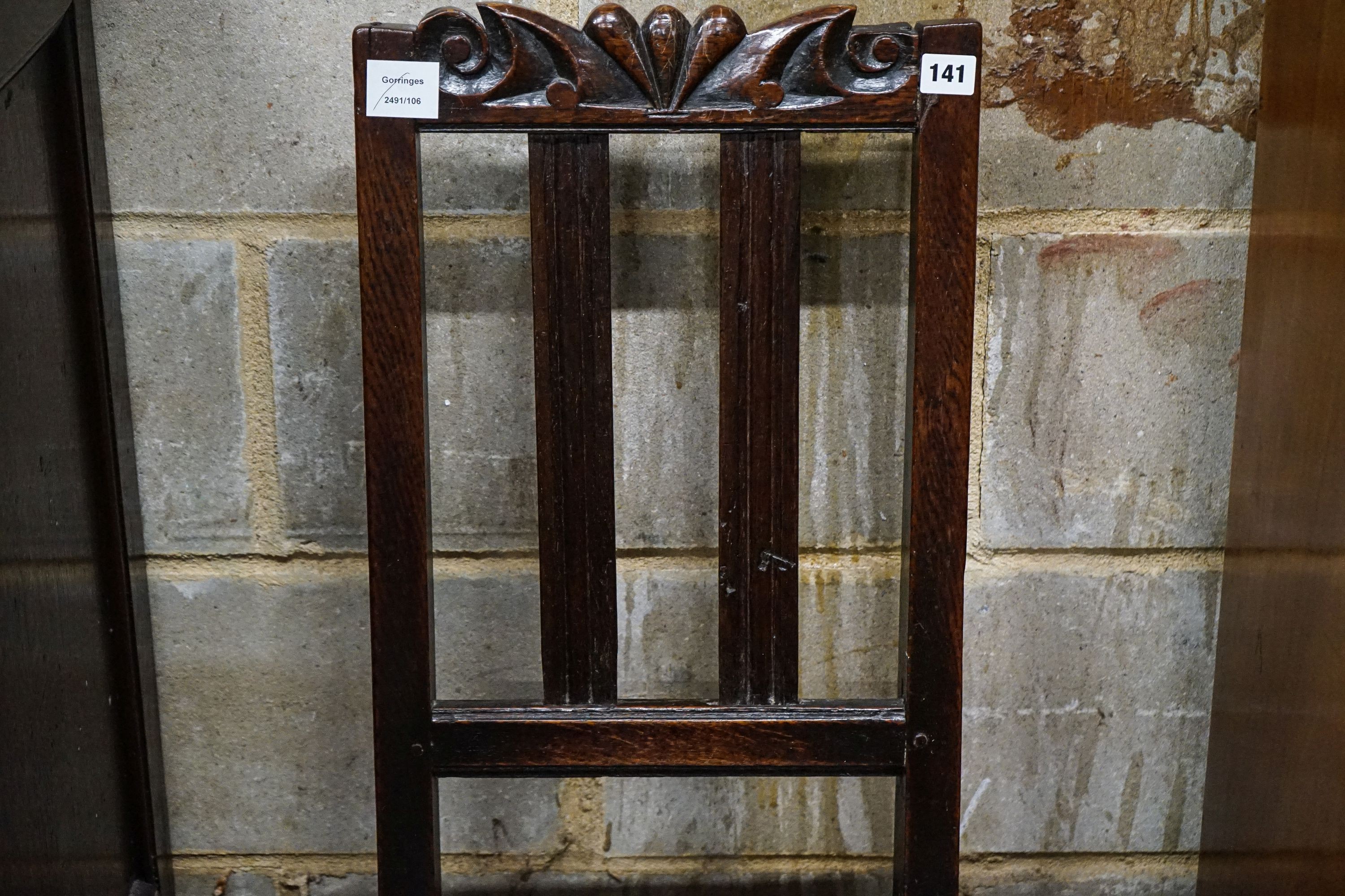 A late 17th century oak back stool, with carved cresting rail, slatted back and solid seat, on turned and square underframe, width 45cm, height 107cm